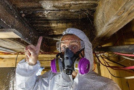 A man wearing a gas mask and goggles is looking under a wooden ceiling
