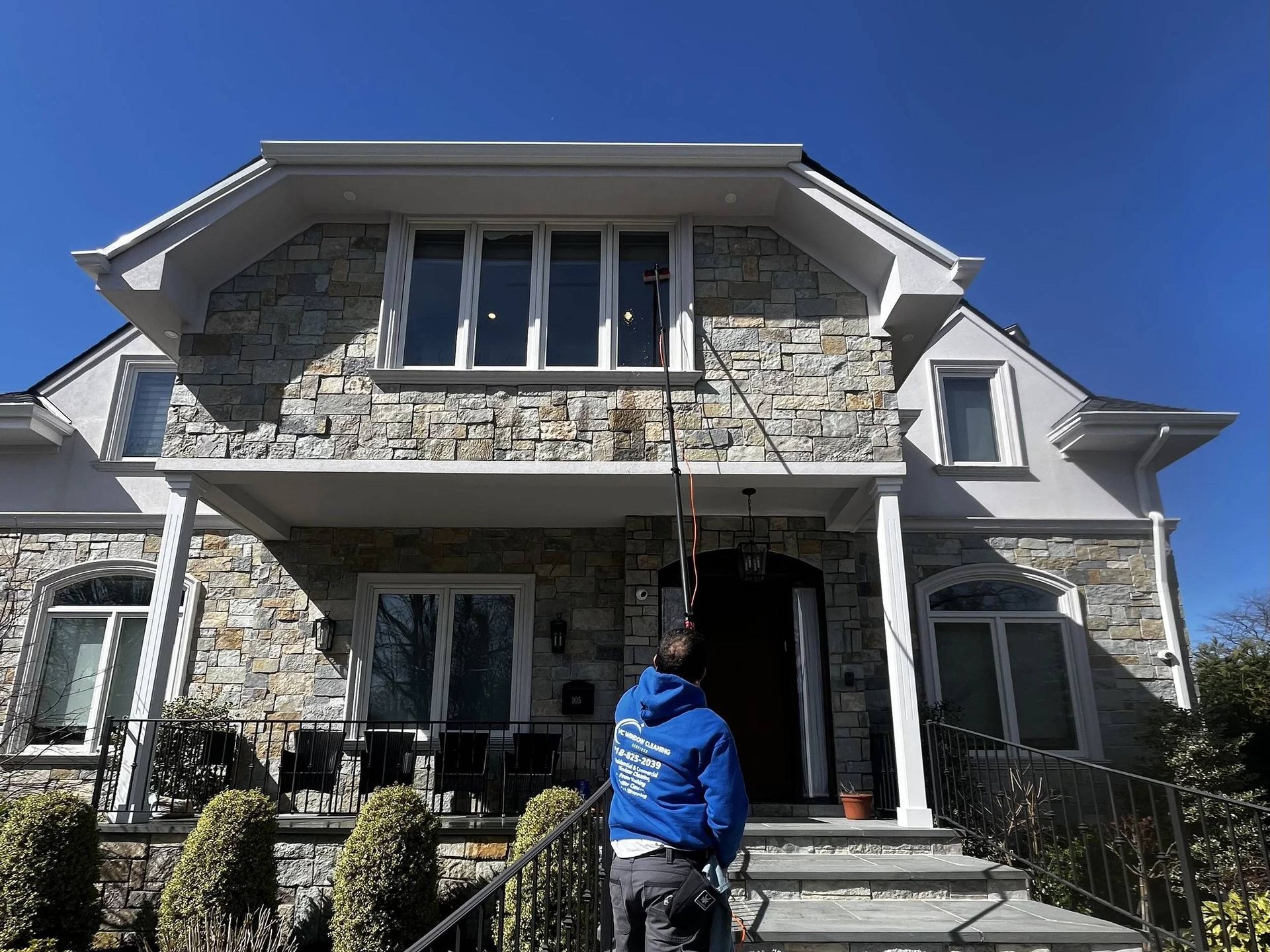 Yellow two-story house with black shutters, green lawn, and blue sky.