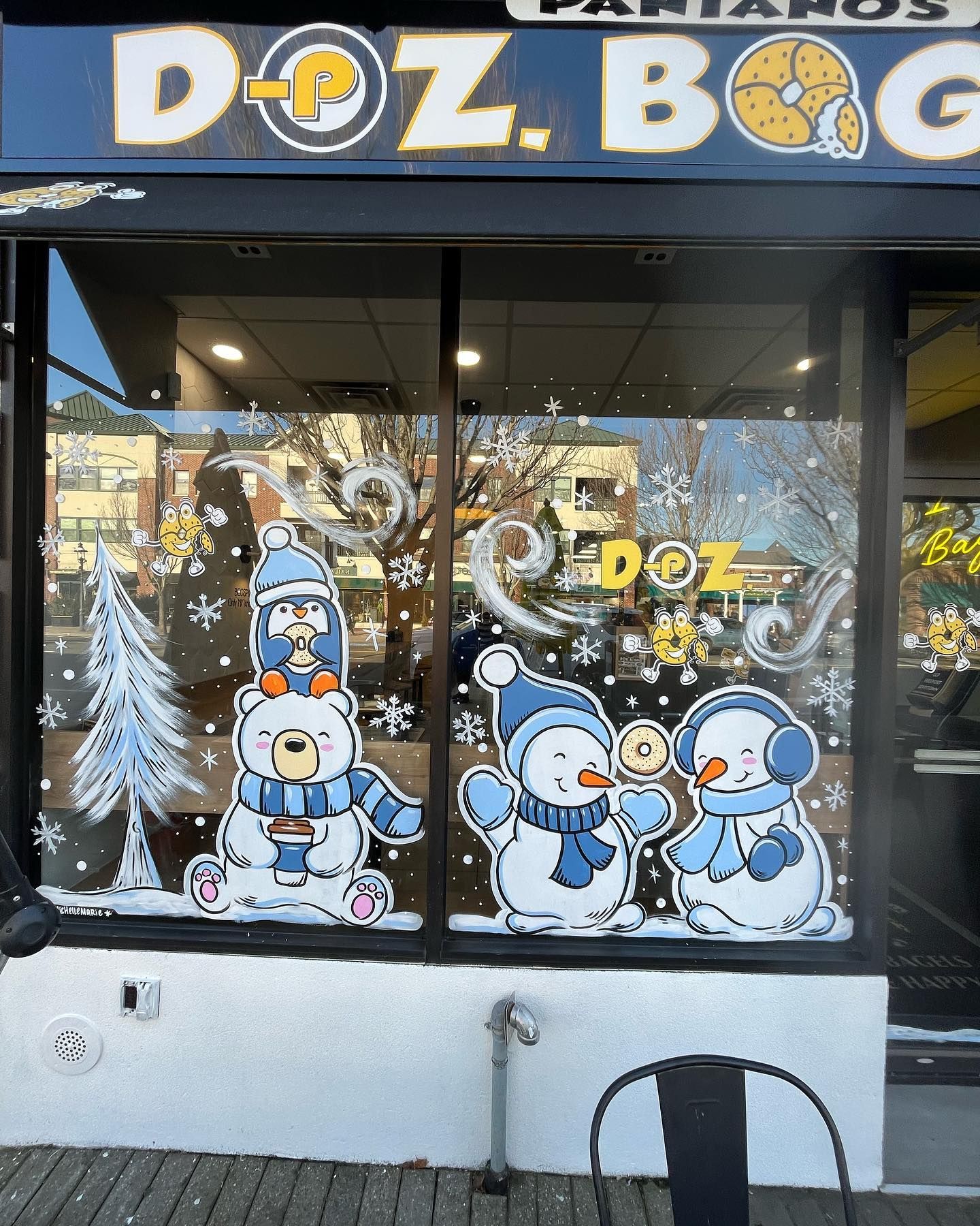 Doz Bagels storefront window with winter decorations: snowmen and bear in blue hats, snowflakes, and the business name.