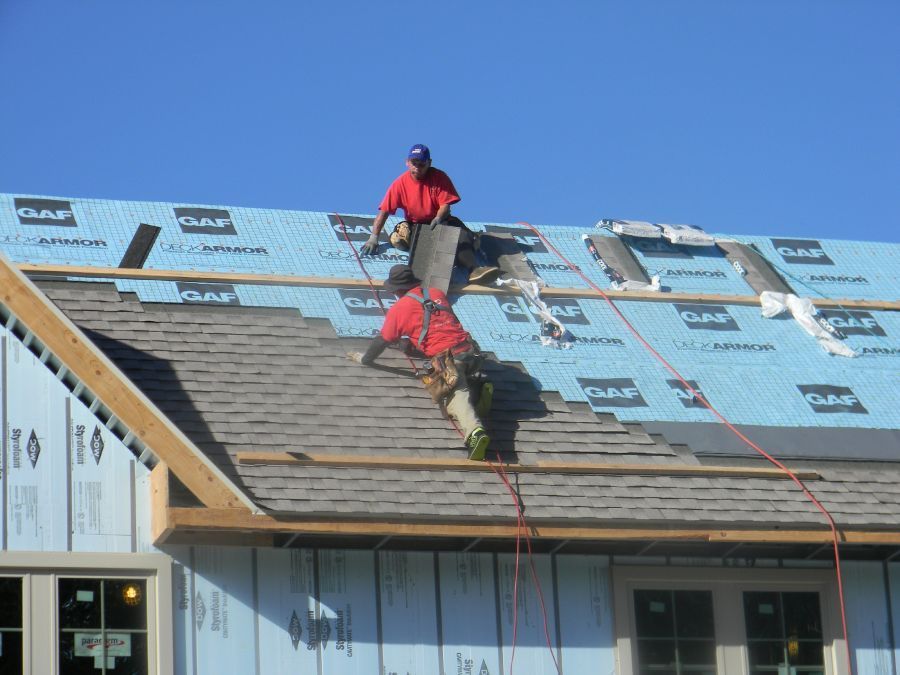 Two men are working on the roof of a house