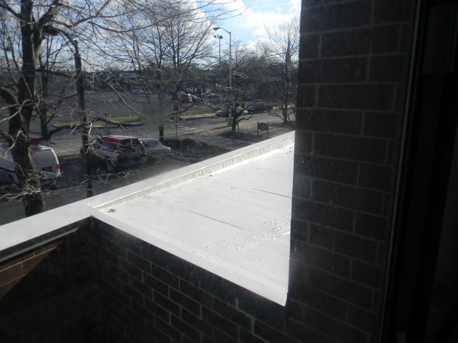 A view of a parking lot from a balcony of a brick building.