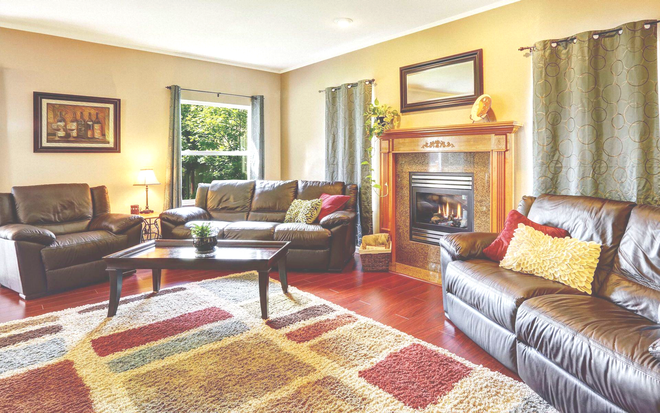 Cozy living room with leather sofas, fireplace, coffee table, and patterned area rug