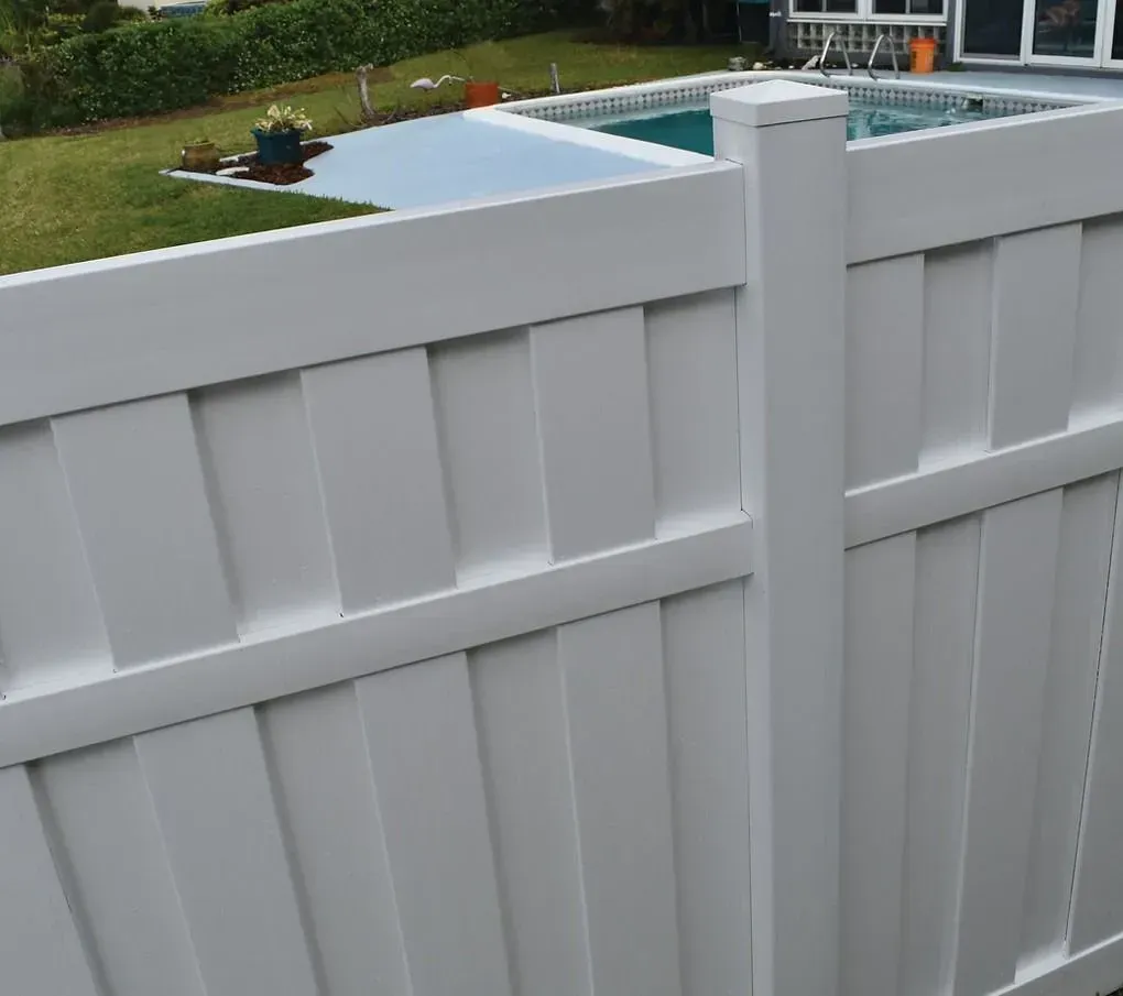 White vinyl fence with a gate overlooking a backyard pool and patio area