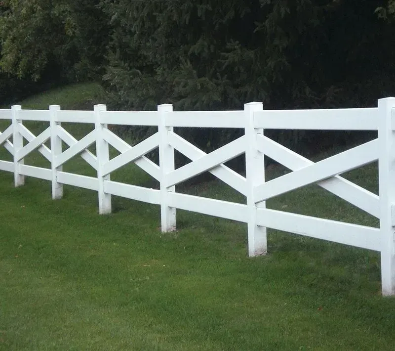 White wooden fence on a green lawn with dark trees in the background