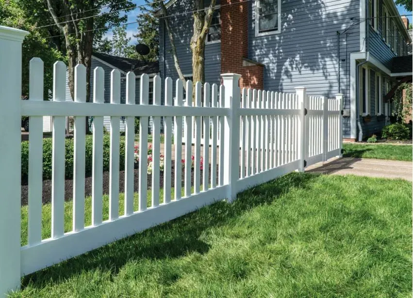 White picket fence along a grassy yard beside a house and sidewalk