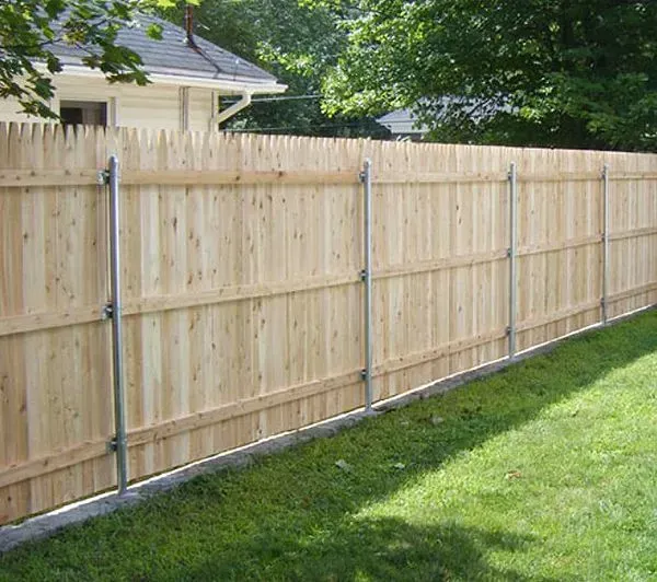 Wooden privacy fence with metal posts along a green lawn in a suburban yard