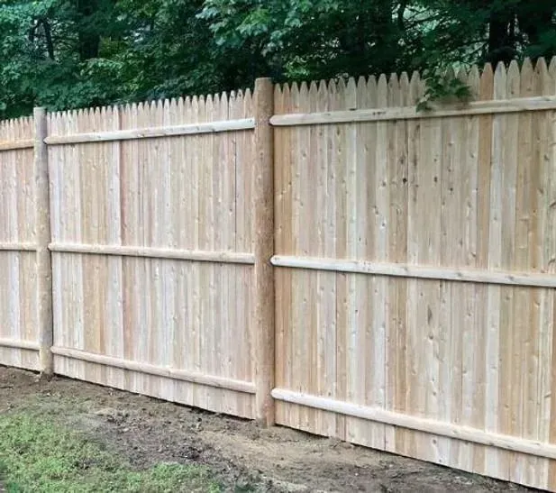 New wooden privacy fence with picket top along a grassy yard