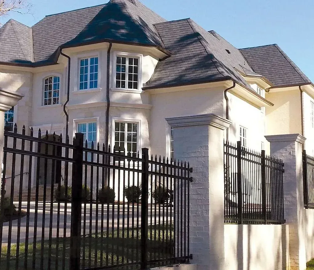 Large cream-colored house with a black metal fence and gate in front