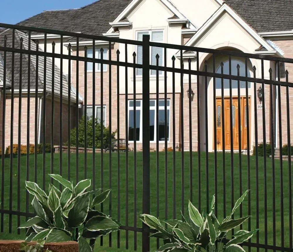 Black metal fence in front of a large beige house with a green lawn and shrubs