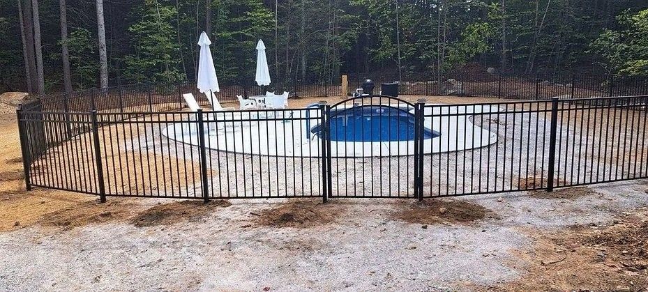 Fenced backyard pool with blue cover and two white patio umbrellas on a gravel deck
