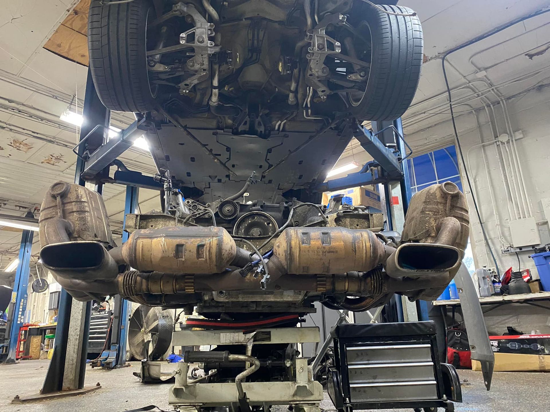 The underside of a car is being worked on in a garage.