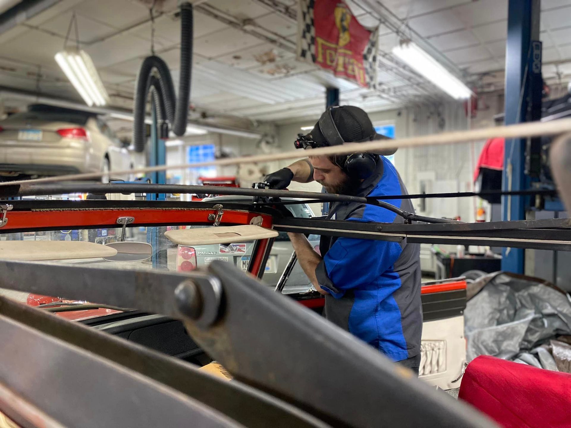 A man wearing headphones is working on a car in a garage.