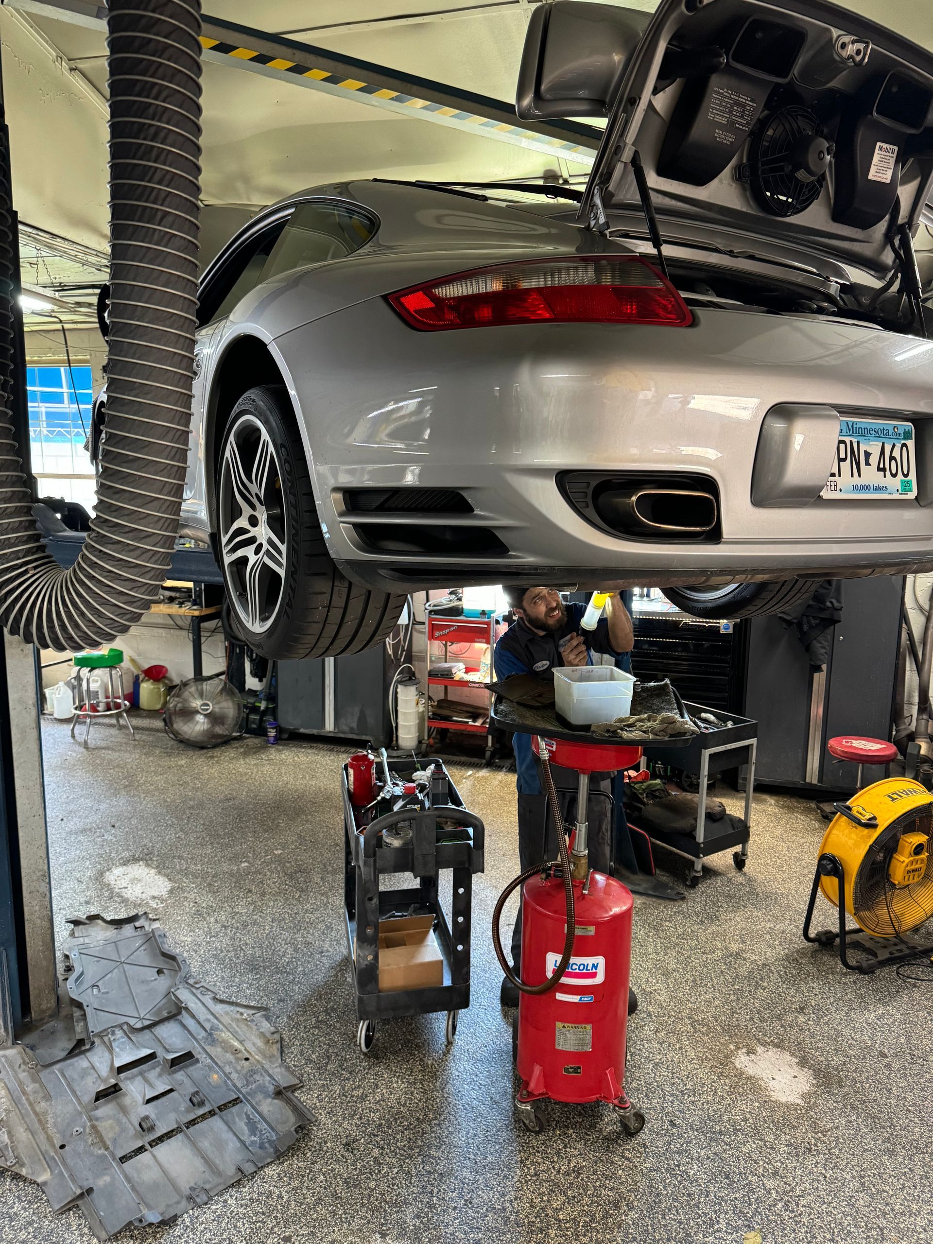 A man is working on a porsche 911 turbo in a garage.