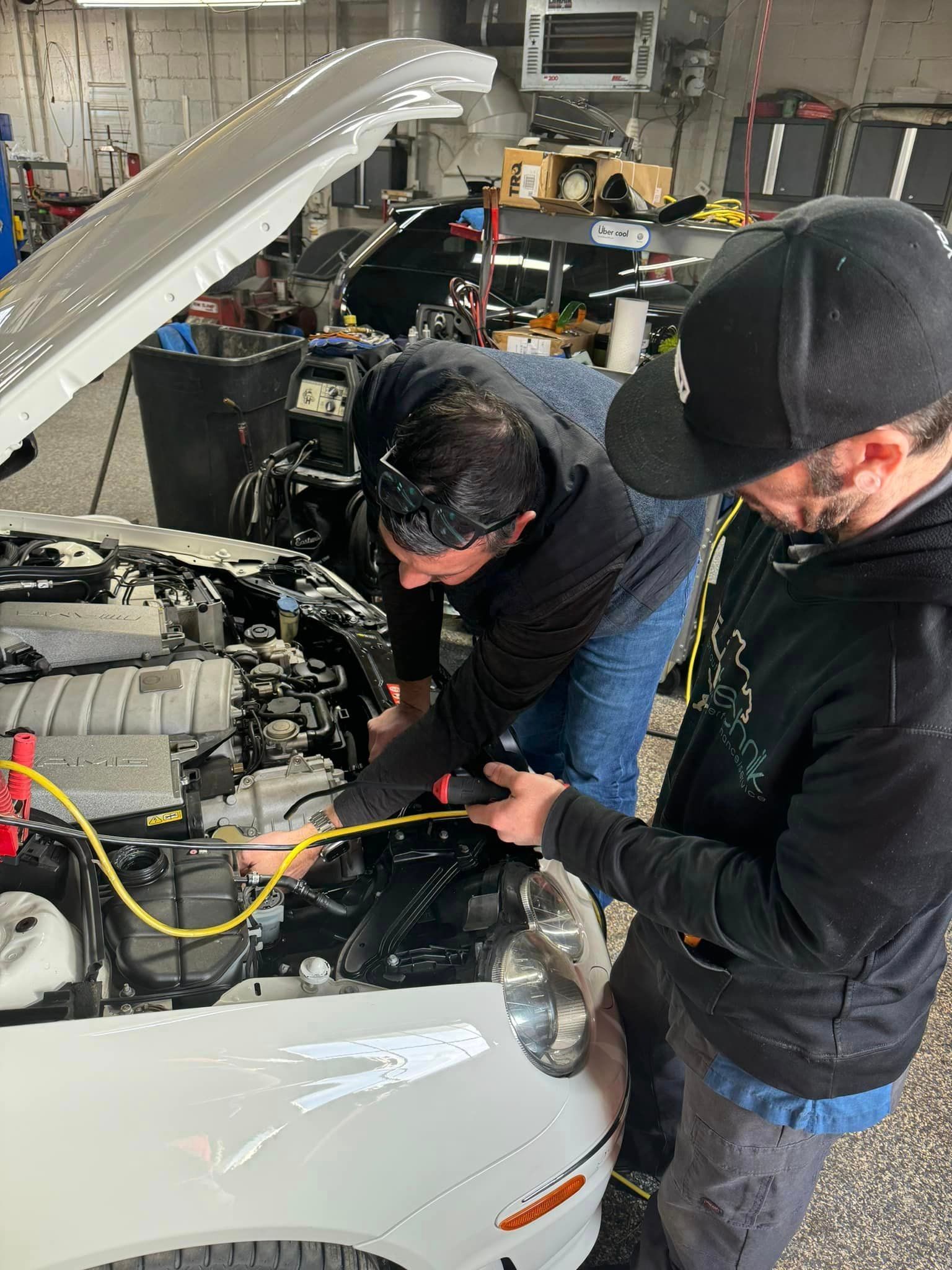 Two men are working on a car in a garage.