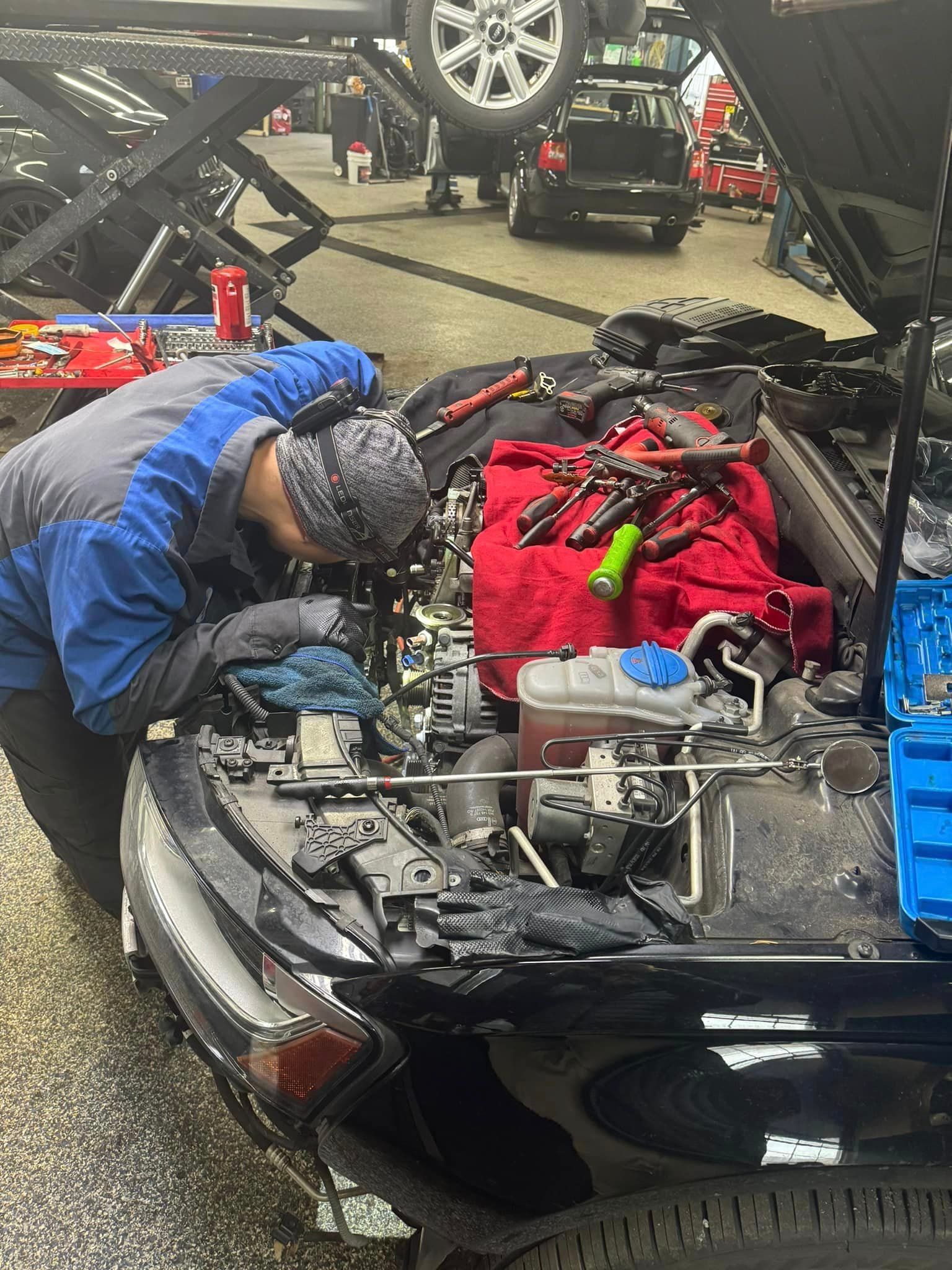 A man is working on the engine of a car in a garage.