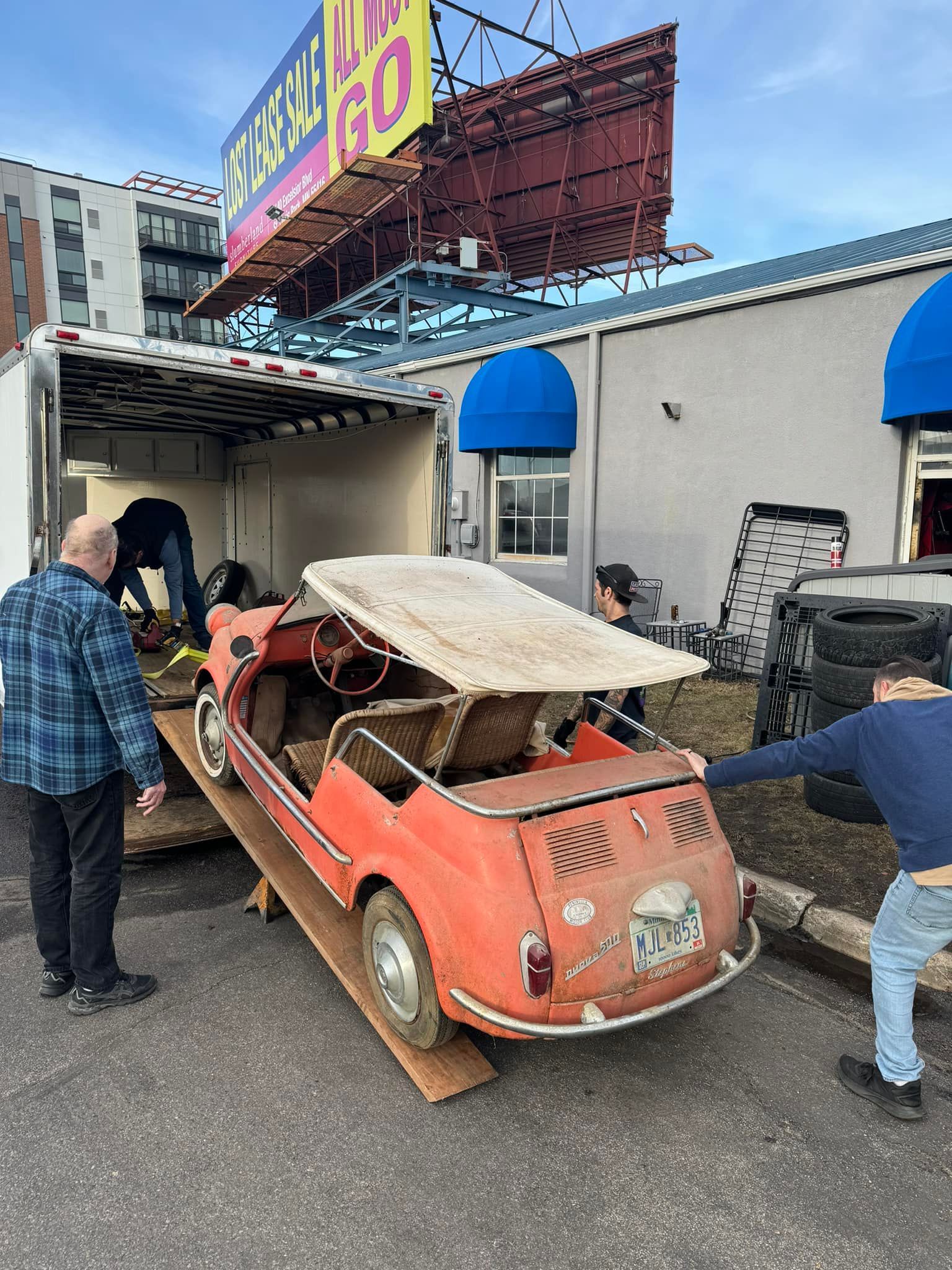 A man is pushing a red car on a ramp.