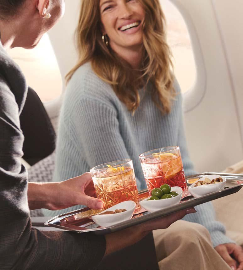 A woman is sitting on an airplane holding a tray of food and drinks