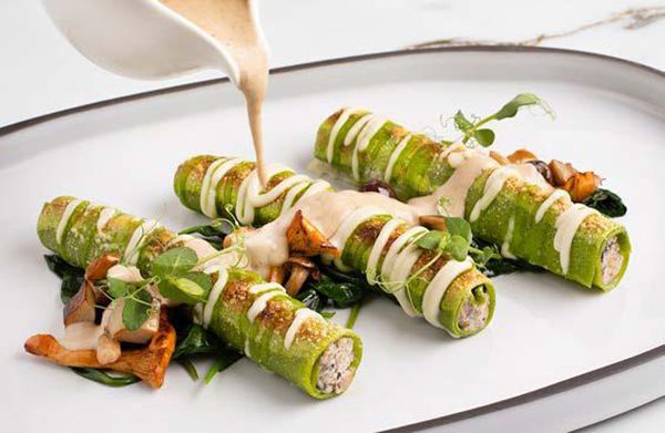 A close up of a plate of food with sauce being poured on it.