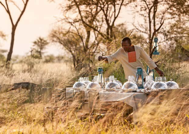 A man is standing in front of a table in a field.