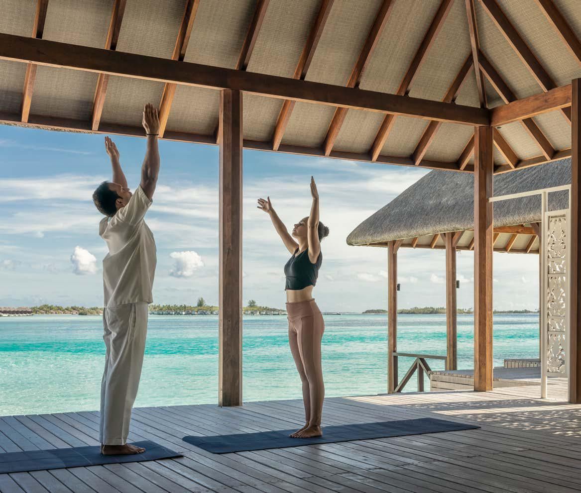 A man and a woman are doing yoga in front of the ocean.