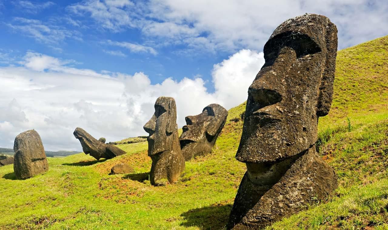 A group of statues sitting on top of a grass covered hill.