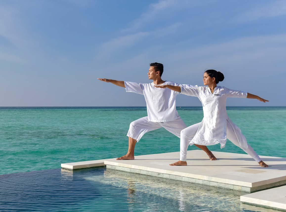 A man and a woman are doing yoga on a dock overlooking the ocean.