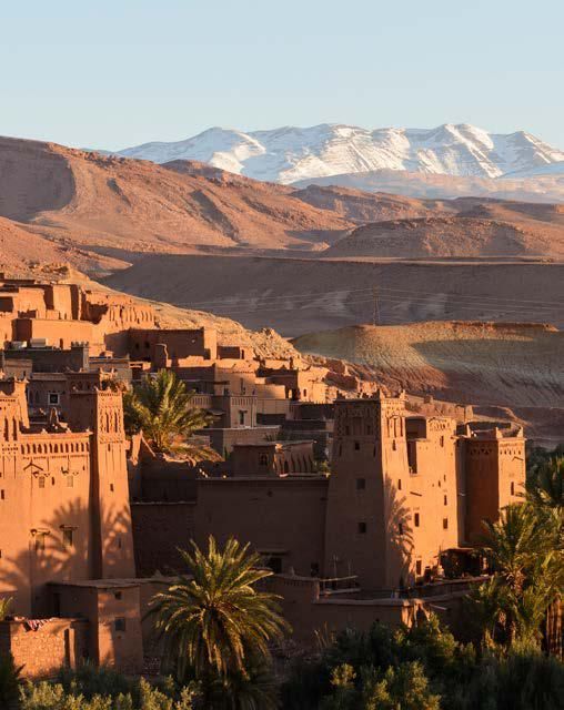 A village in the middle of a desert with mountains in the background