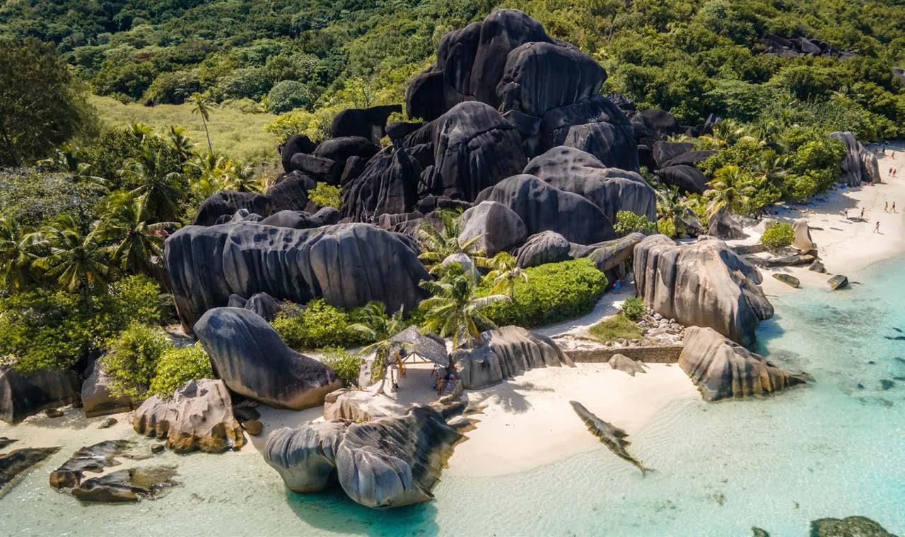 An aerial view of a beach surrounded by rocks and trees.