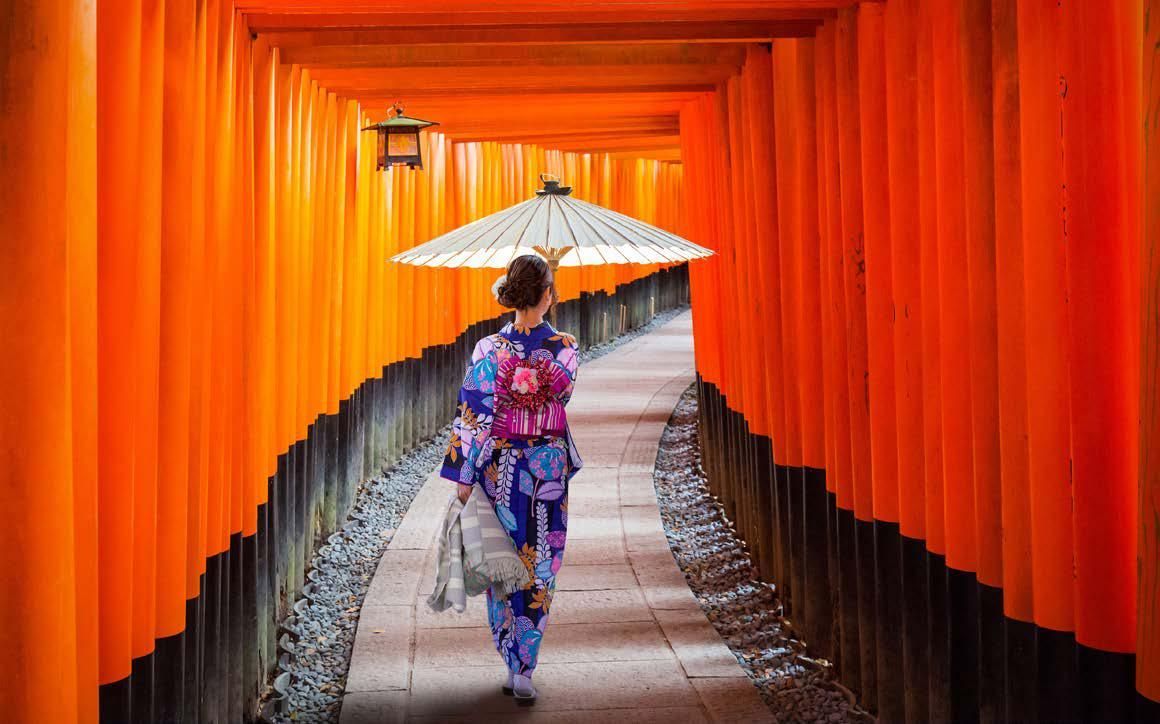 A woman in a kimono is walking down a path with an umbrella.
