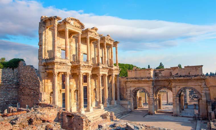 A very old building with columns and arches in the middle of a ruined city.