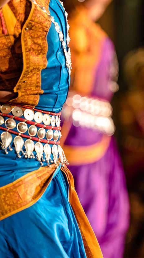 A woman in a blue and gold dress is dancing.