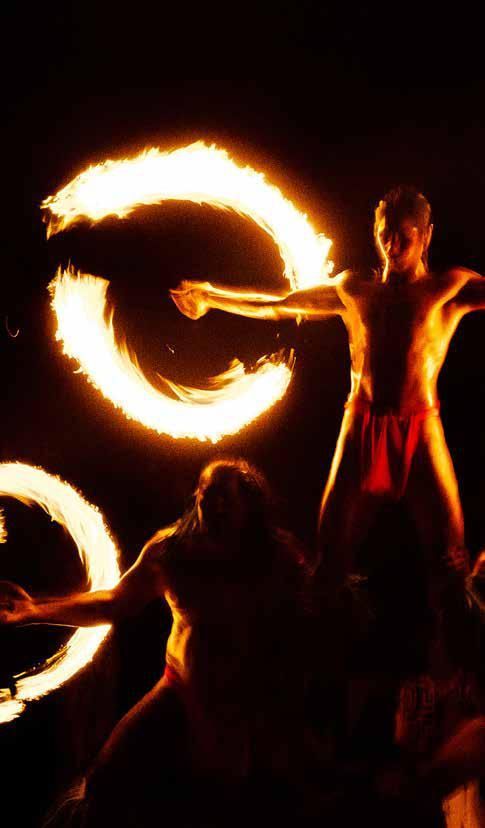 A group of people are performing a fire show in the dark.