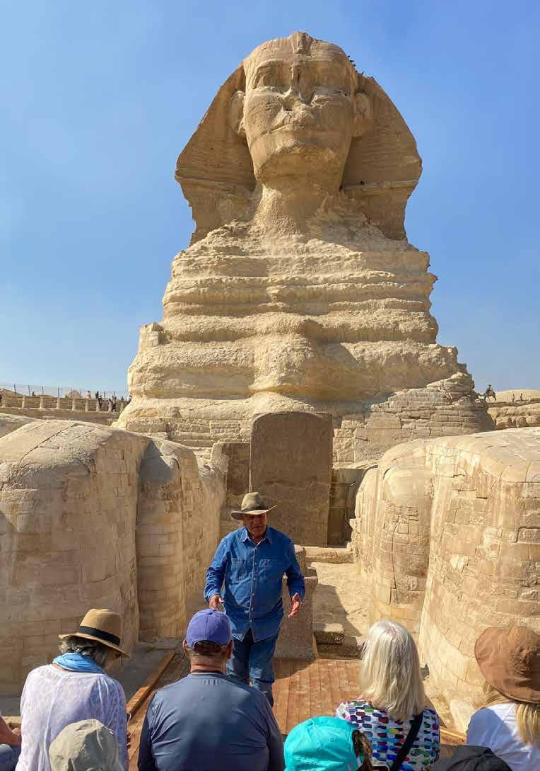A group of people are standing in front of a statue of a sphinx.