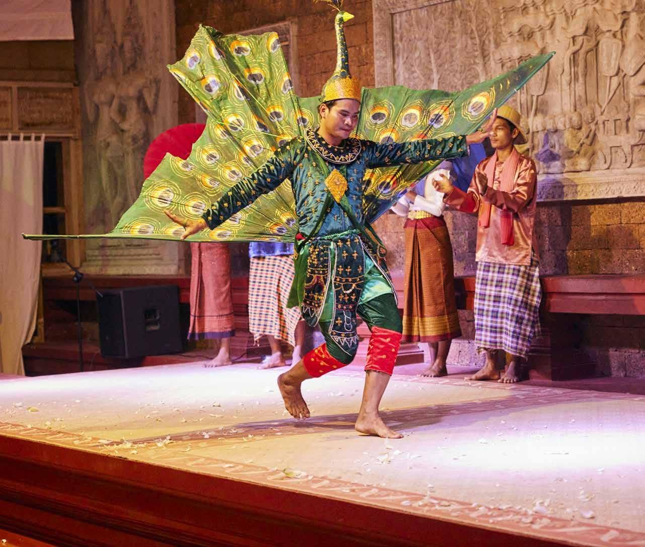 A man in a peacock costume is dancing on a stage