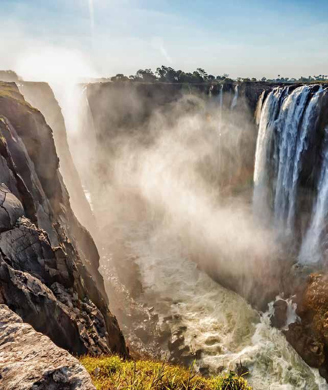 A waterfall surrounded by rocks and trees on a sunny day.