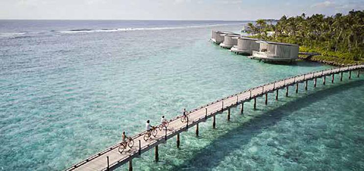 A group of people are riding bikes on a dock in the ocean.