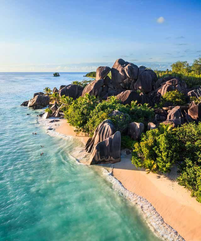 An aerial view of a tropical beach surrounded by rocks and trees.