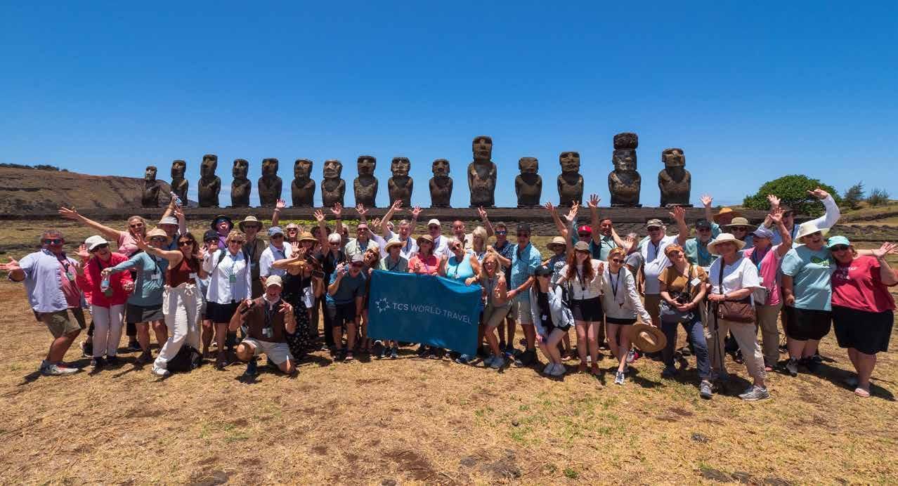 A large group of people are posing for a picture in front of a row of statues.