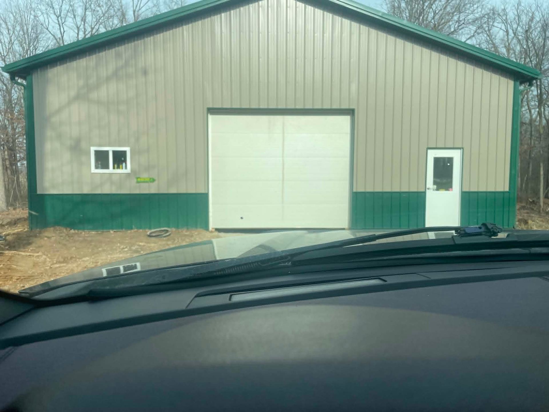 Metal garage with green trim and white doors, seen from inside a car.