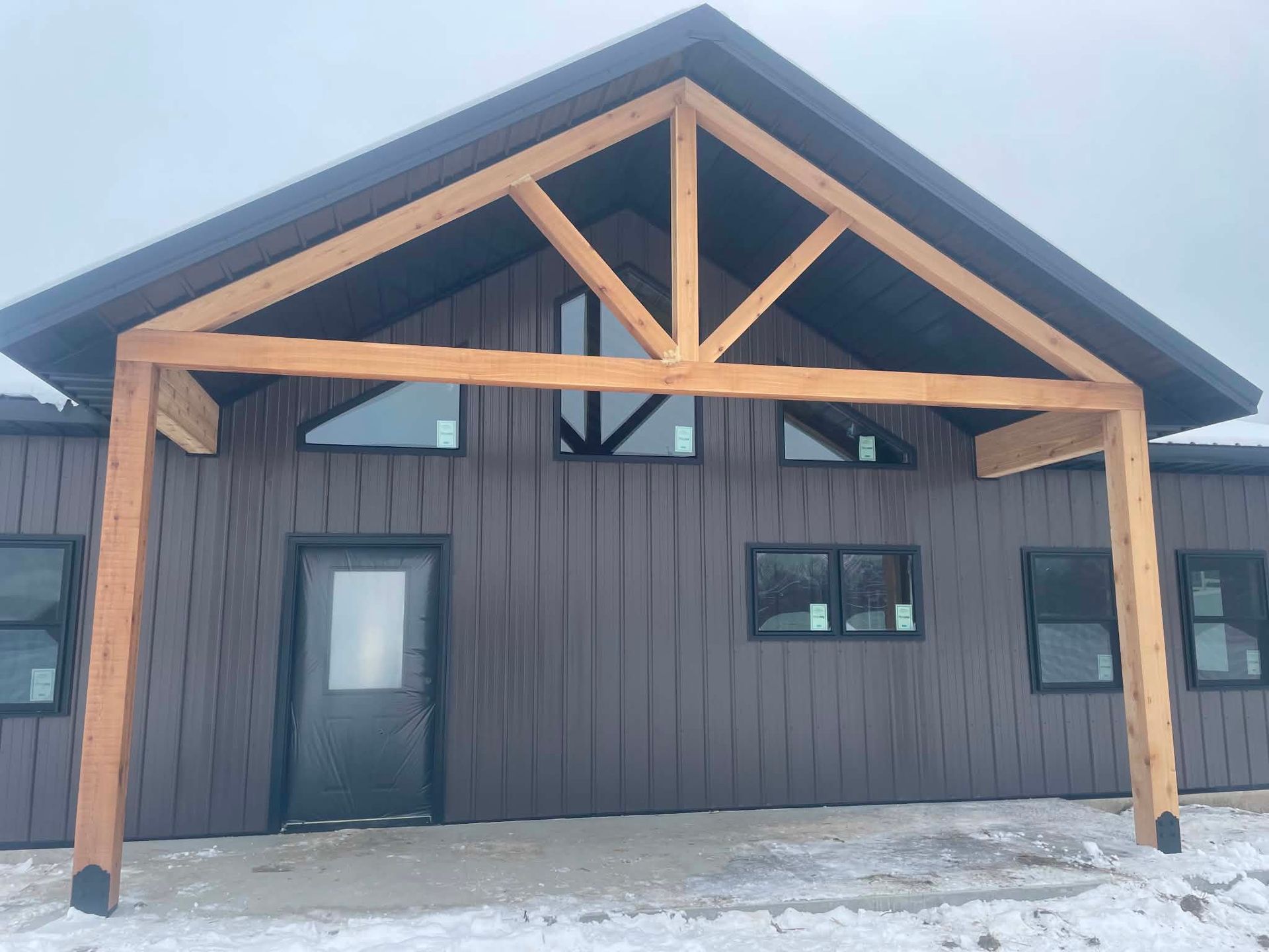 Dark wood cabin exterior with exposed timber trusses and snow on the ground