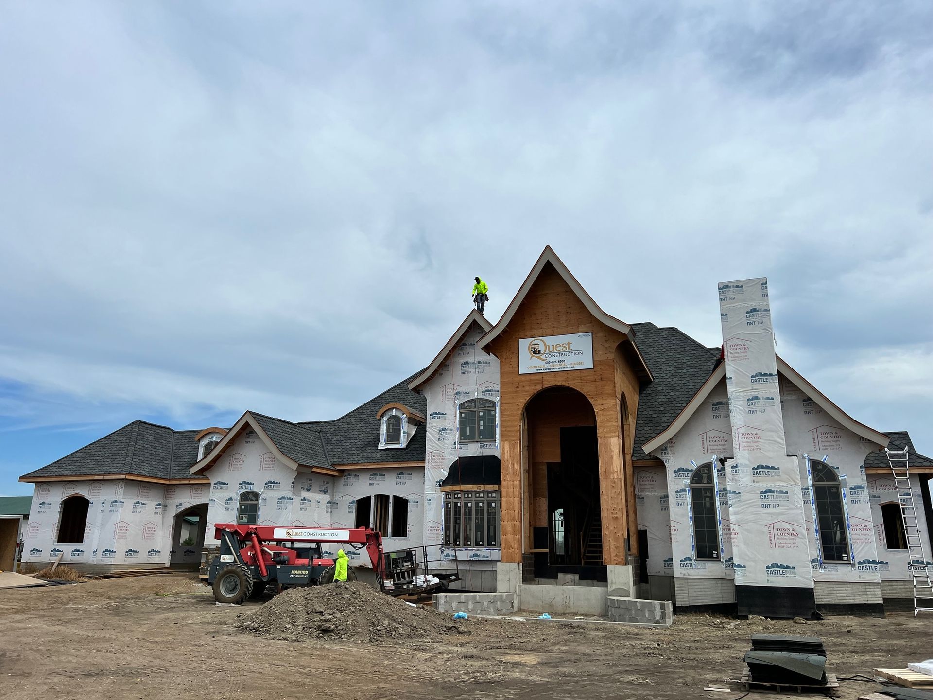 A white house with a red roof and a man sitting on the porch.
