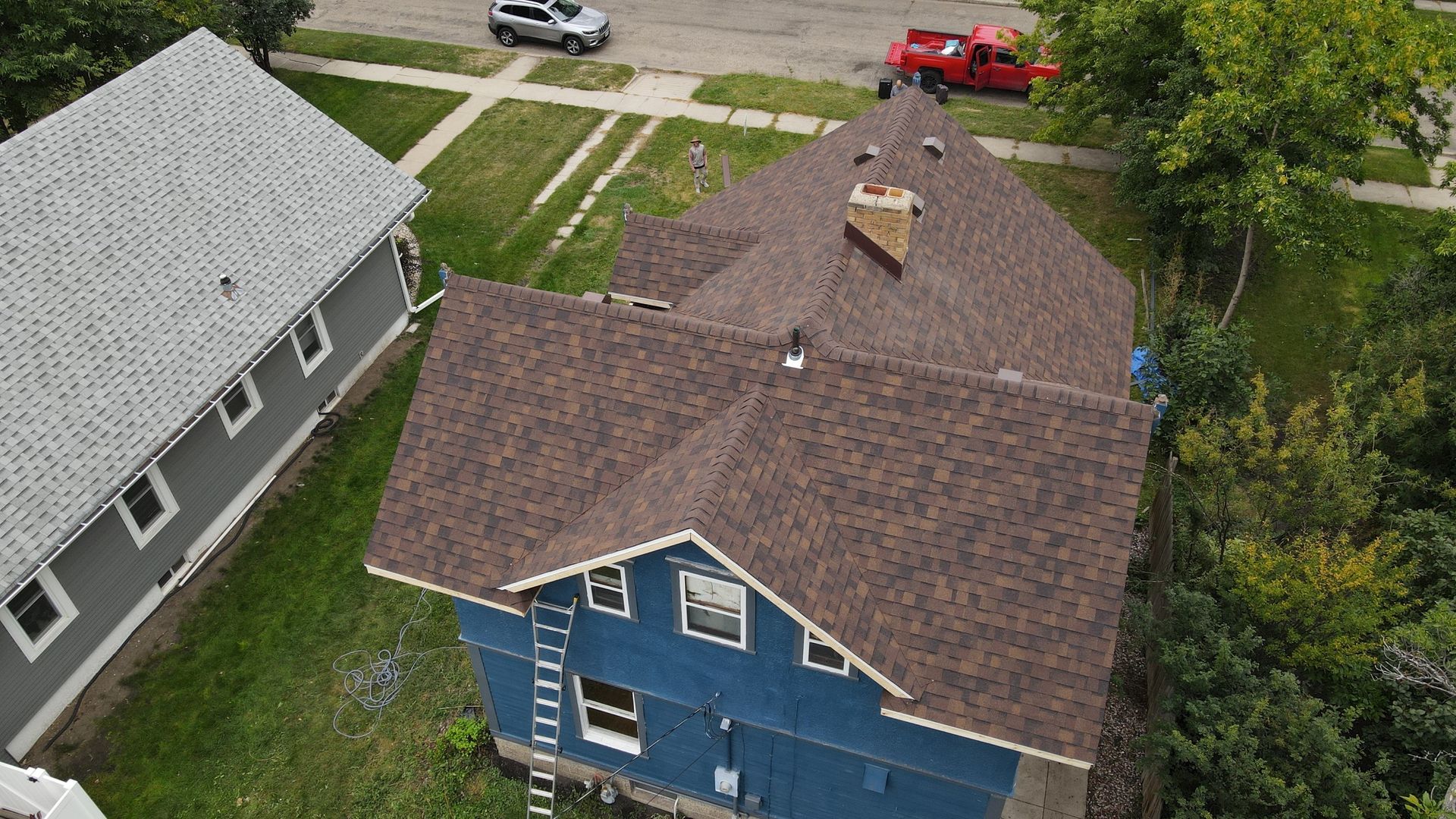A man is working on the roof of a brick house.
