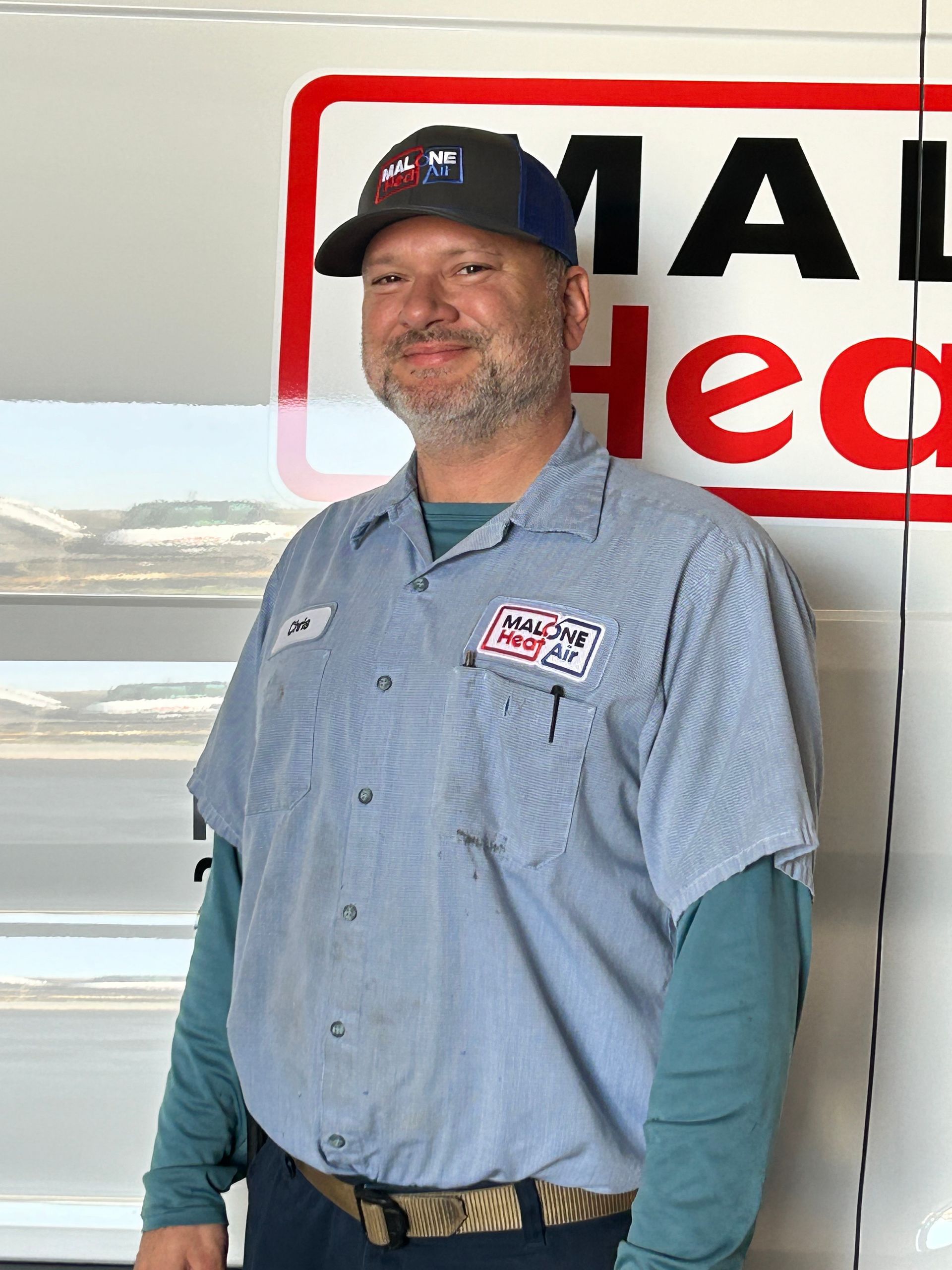 Man in work uniform stands near a truck with 