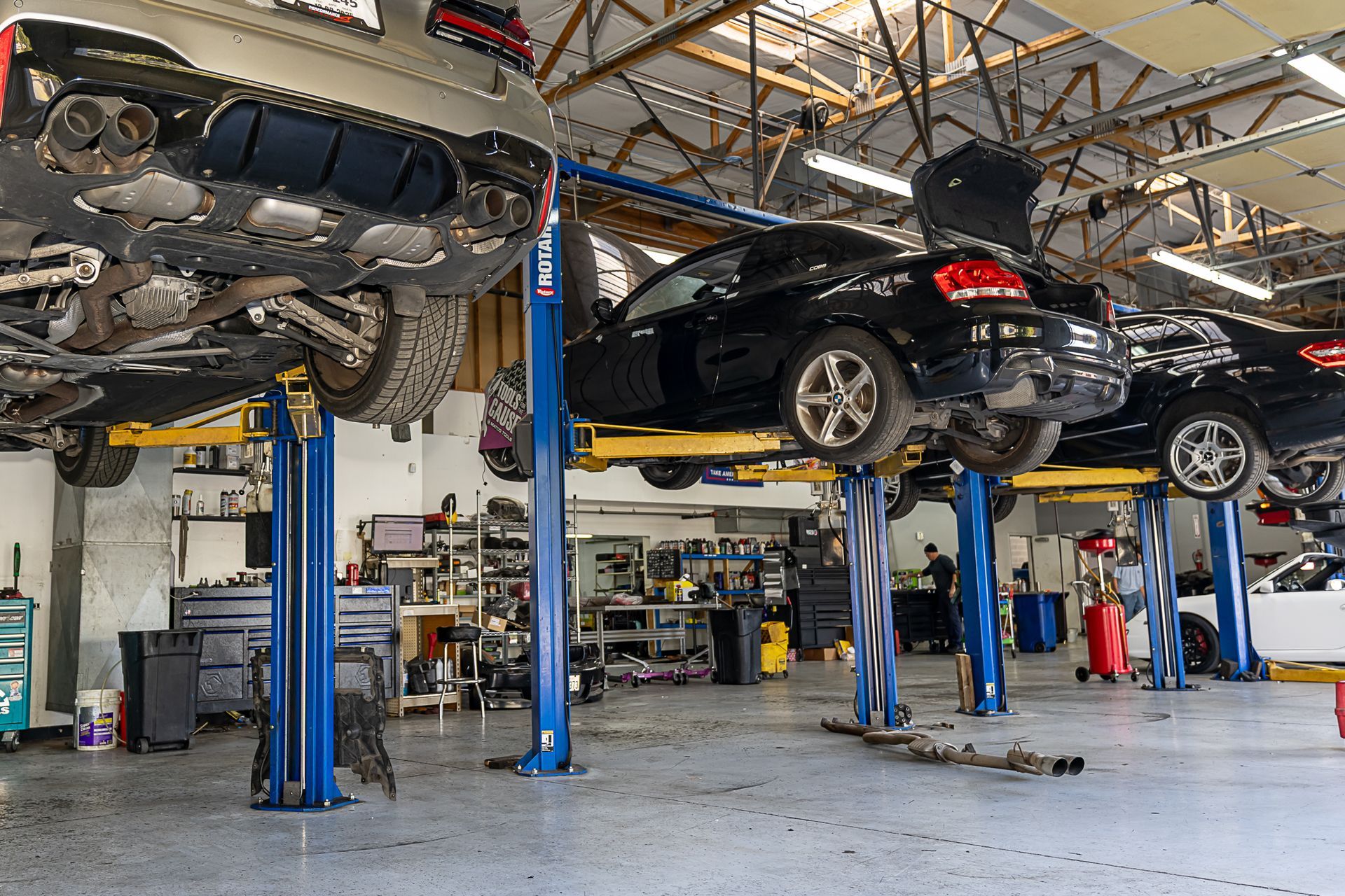 Cars on lifts in a busy auto repair shop, with tools and equipment scattered around.