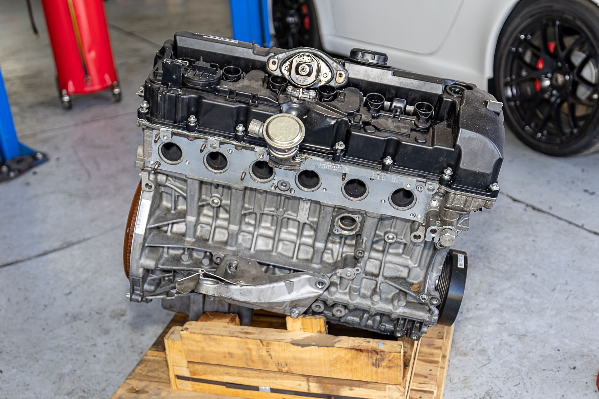 Engine on a wooden pallet in a garage, black and silver components, mechanic setting.