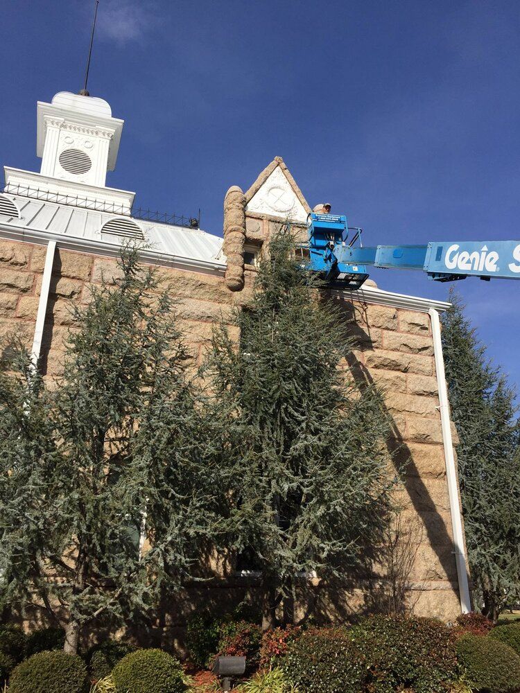 A man is standing on a crane on top of a building.