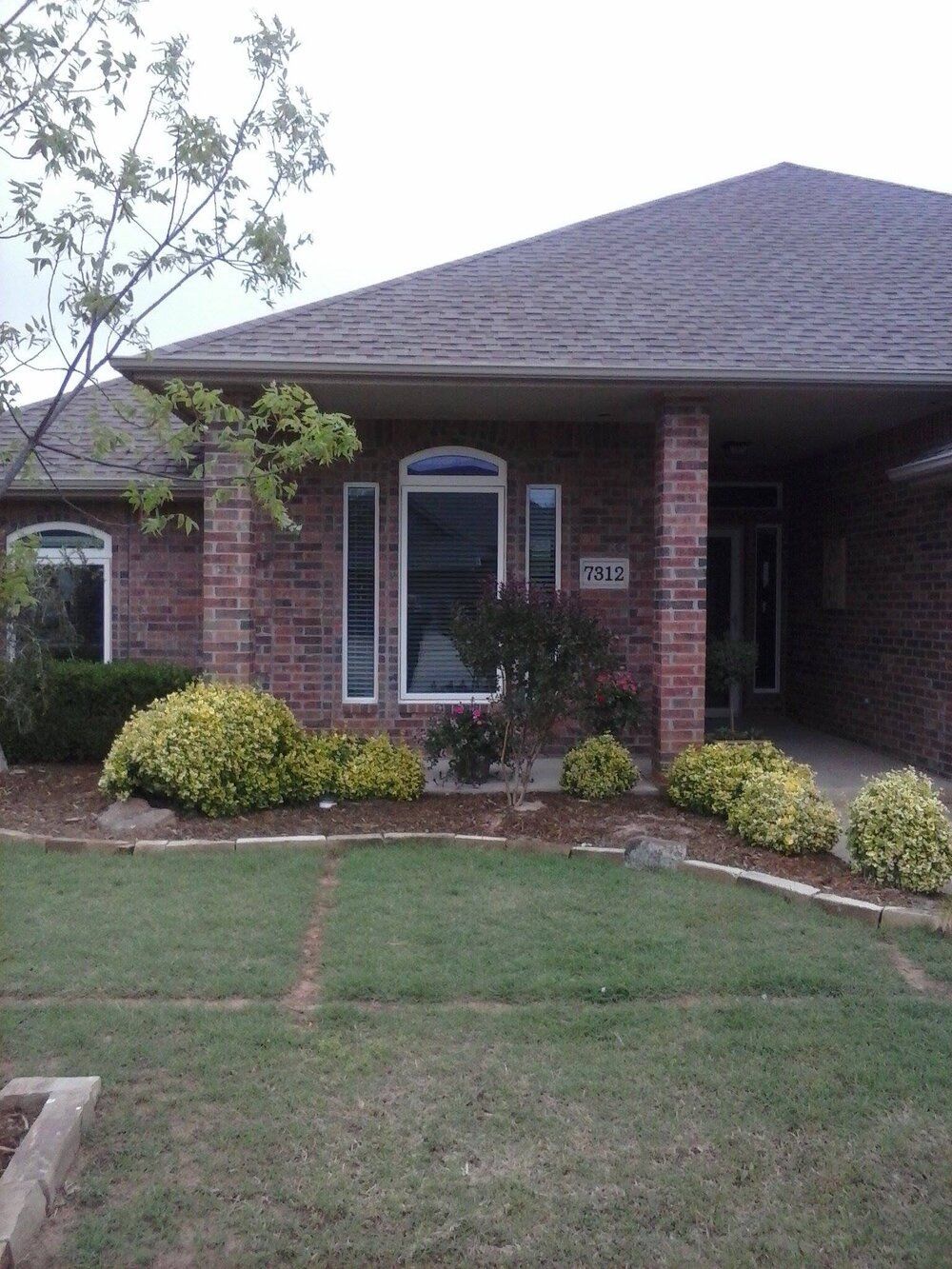 A brick house with a large lawn in front of it