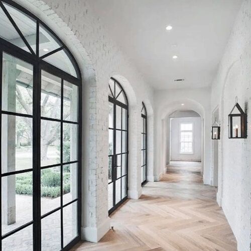 A long hallway with arched windows and a wooden floor.