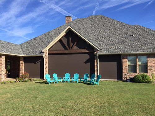 A row of blue chairs are sitting in front of a house.