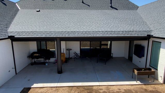 The backyard of a house with a covered patio and a gray roof.